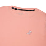 Close-up of the small white embroidered logo on the front of the light pink t-shirt.