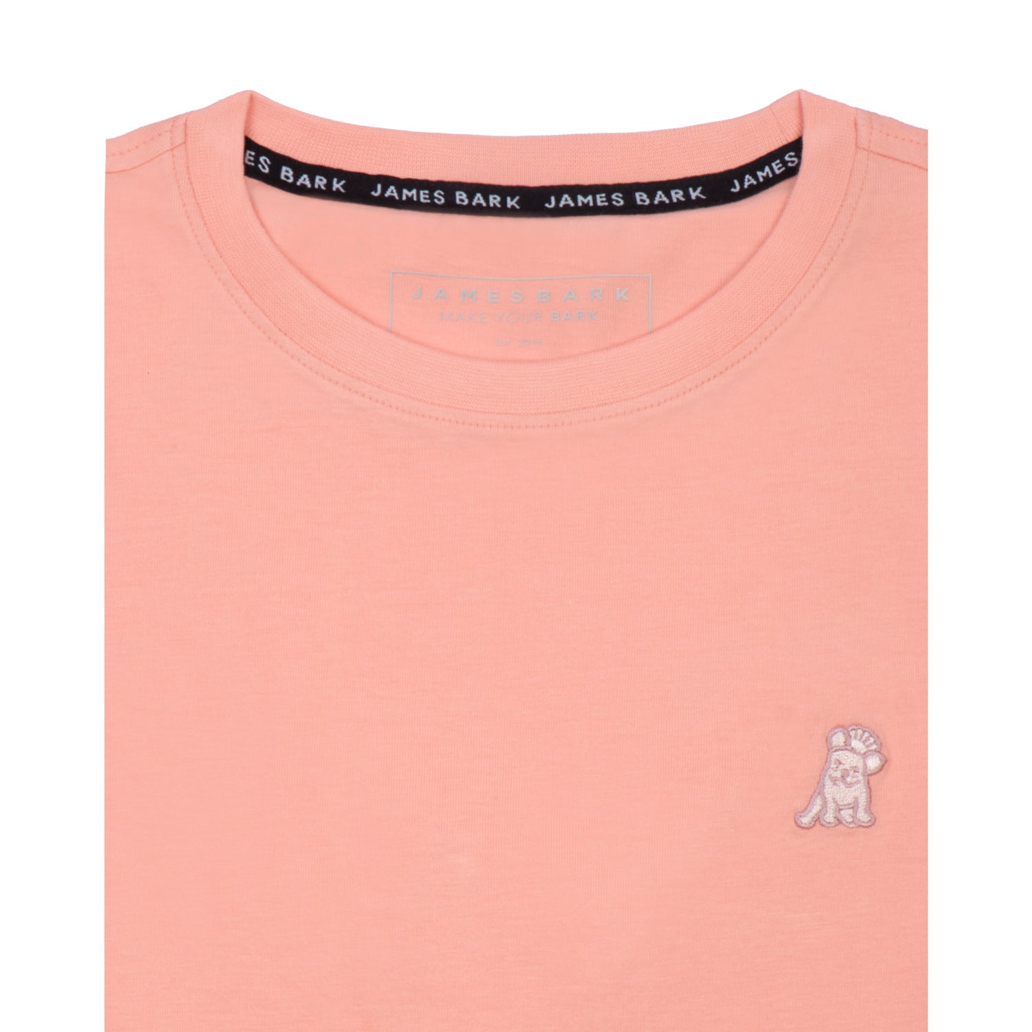 Close-up of the collar area of the light pink t-shirt, showing the small white embroidered logo on the chest.