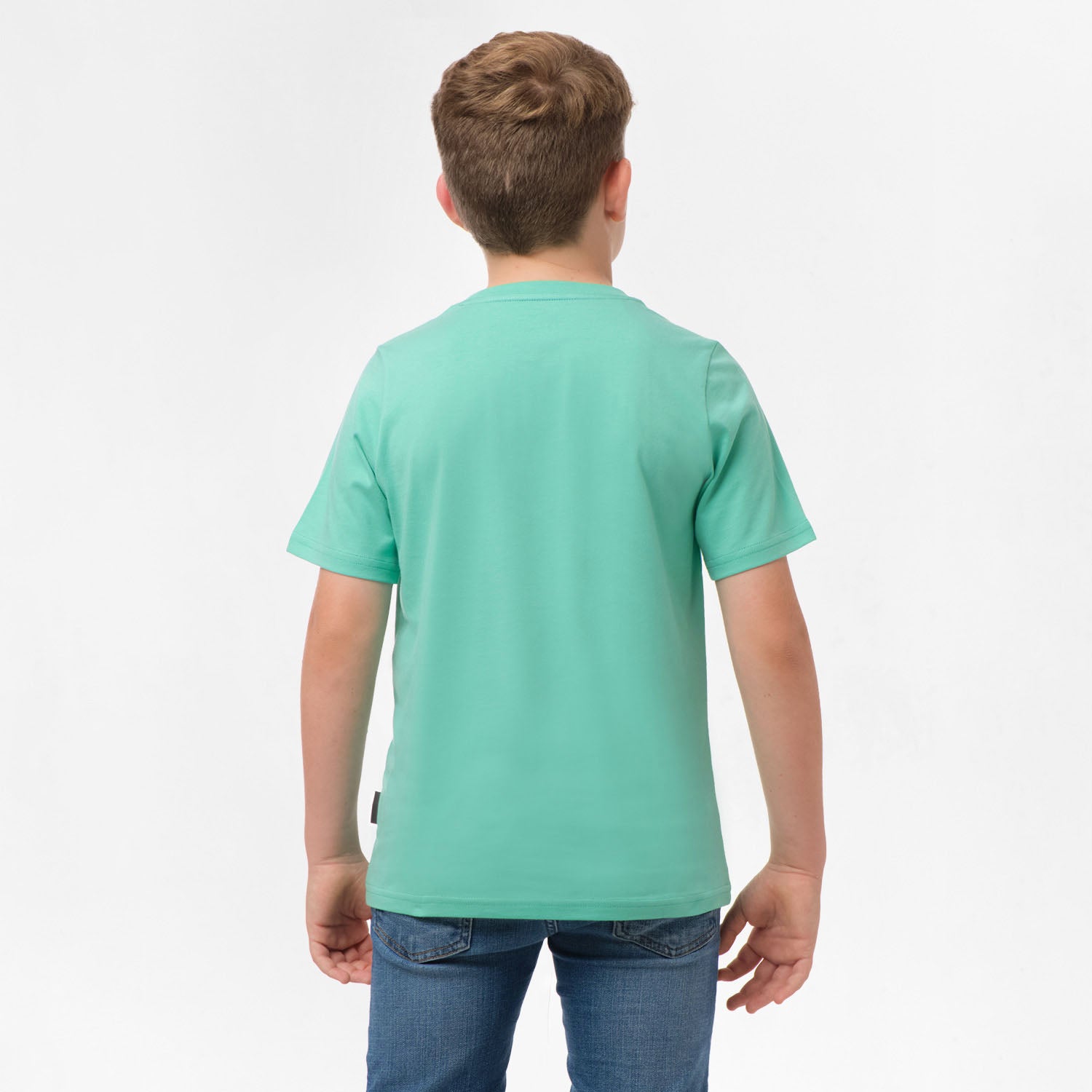 Rear view of a boy wearing the mint green t-shirt, standing with his hands behind his back.