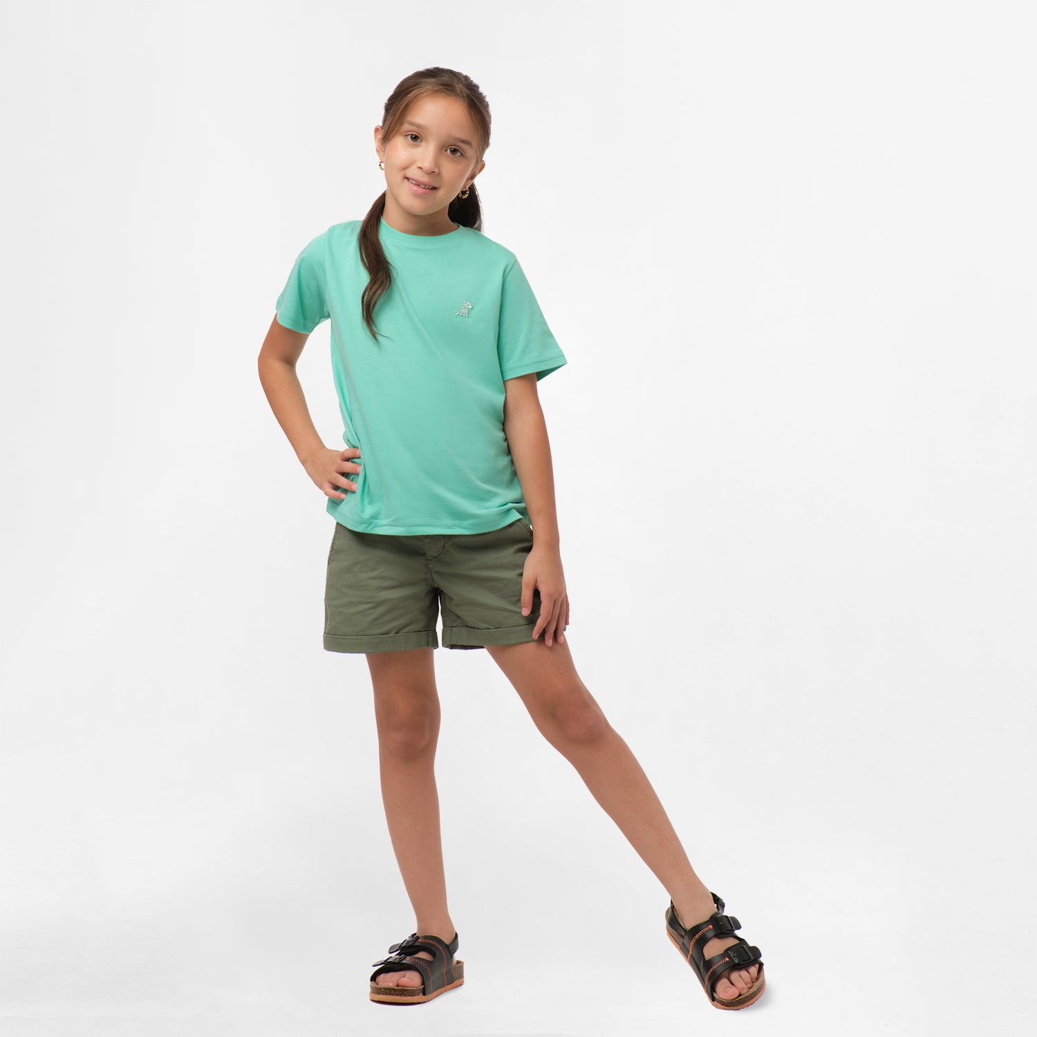 Full-body view of a girl wearing the mint green t-shirt and olive green shorts, standing with one hand in her pocket and the other resting on her hi