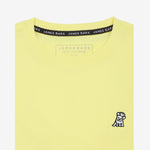 Close-up of the collar area of the light yellow t-shirt, showing the small white embroidered logo on the chest.