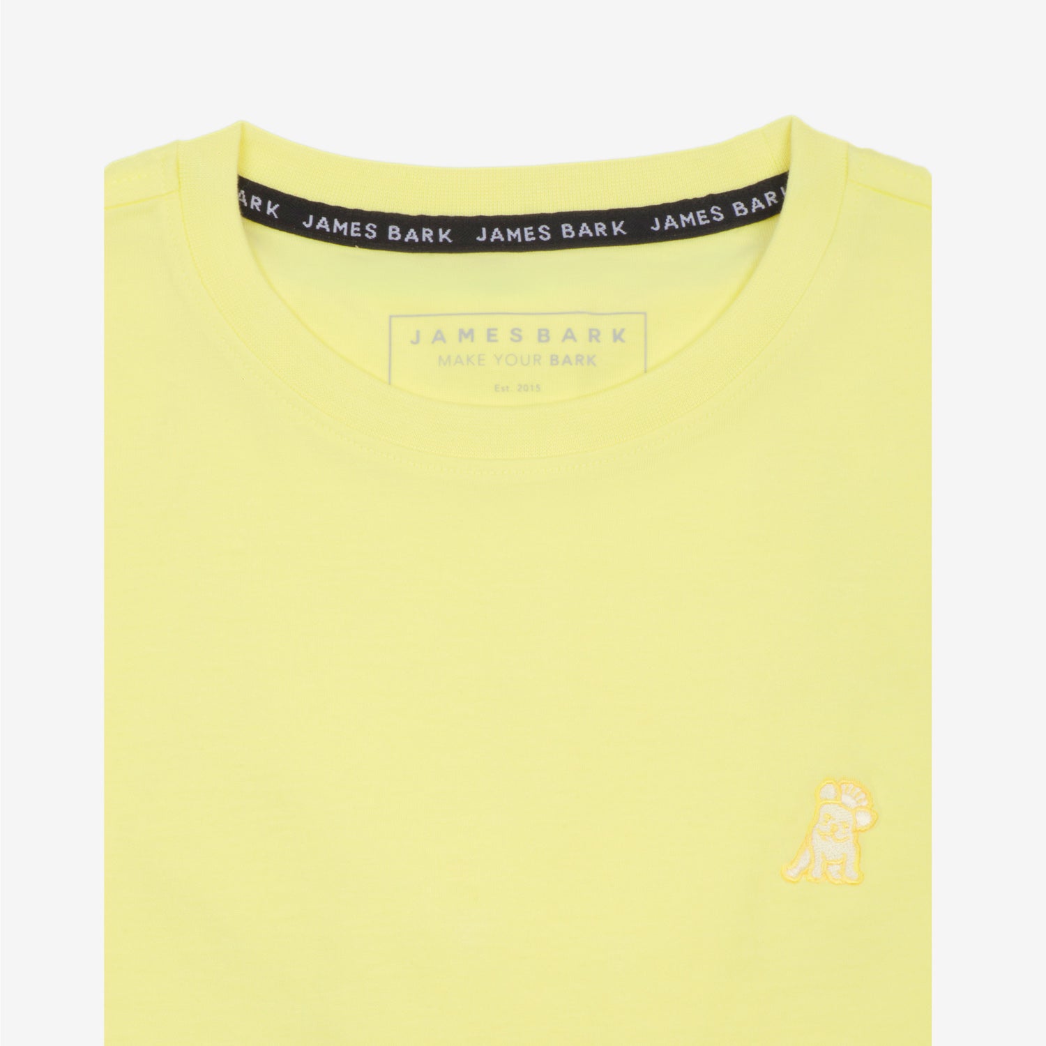 Close-up of the collar area of the light yellow t-shirt, showing the small embroidered logo on the chest.