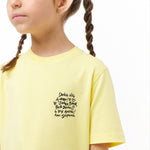 Close-up side view of the girl wearing the yellow T-shirt, highlighting the text graphic on the chest.