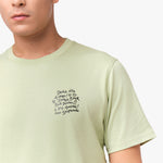 Close-up of the light green t-shirt's left chest, showing the black graphic design.