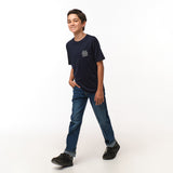 Full view of the young boy wearing the navy blue T-shirt with blue jeans, standing with one foot slightly forward.