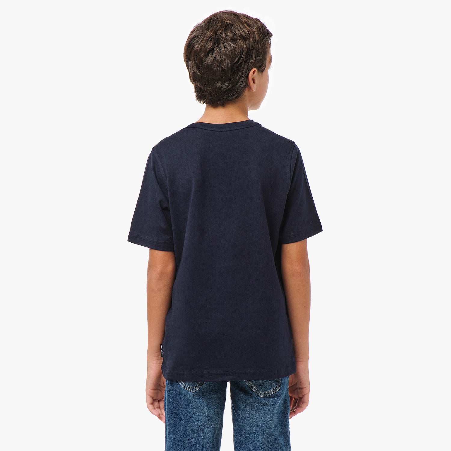 Back view of a young boy wearing the navy blue T-shirt with blue jeans