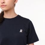 Close-up side view of the woman wearing the navy blue T-shirt, highlighting the small decorative 'JB' logo on the chest.