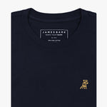 Close-up of the chest area of the navy blue t-shirt: A detailed view of the small embroidered dog logo in gold on the left chest, contrasting against the navy blue fabric.