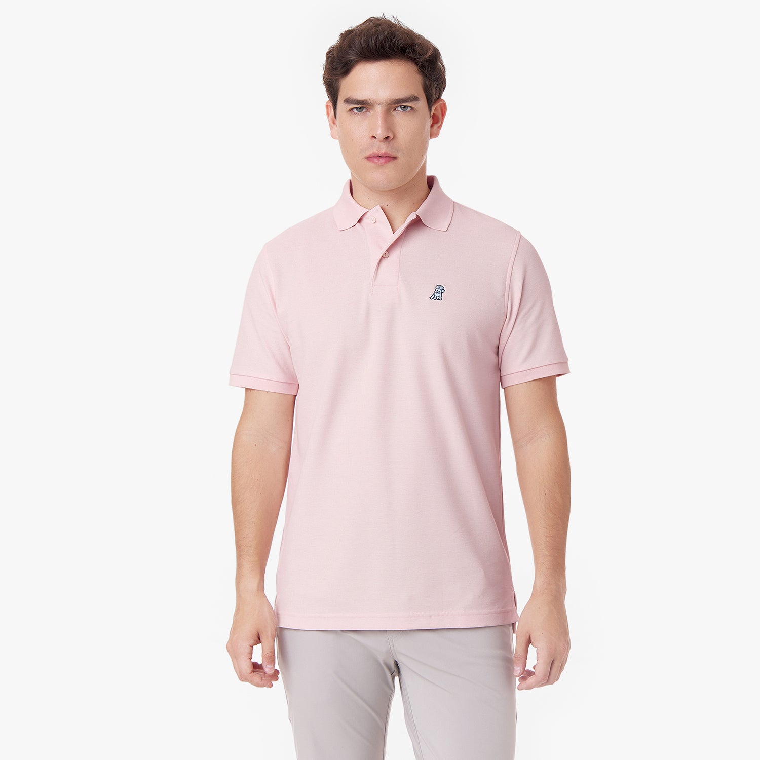 Male model wearing a pink polo shirt and light grey pants, standing front view looking at the camera