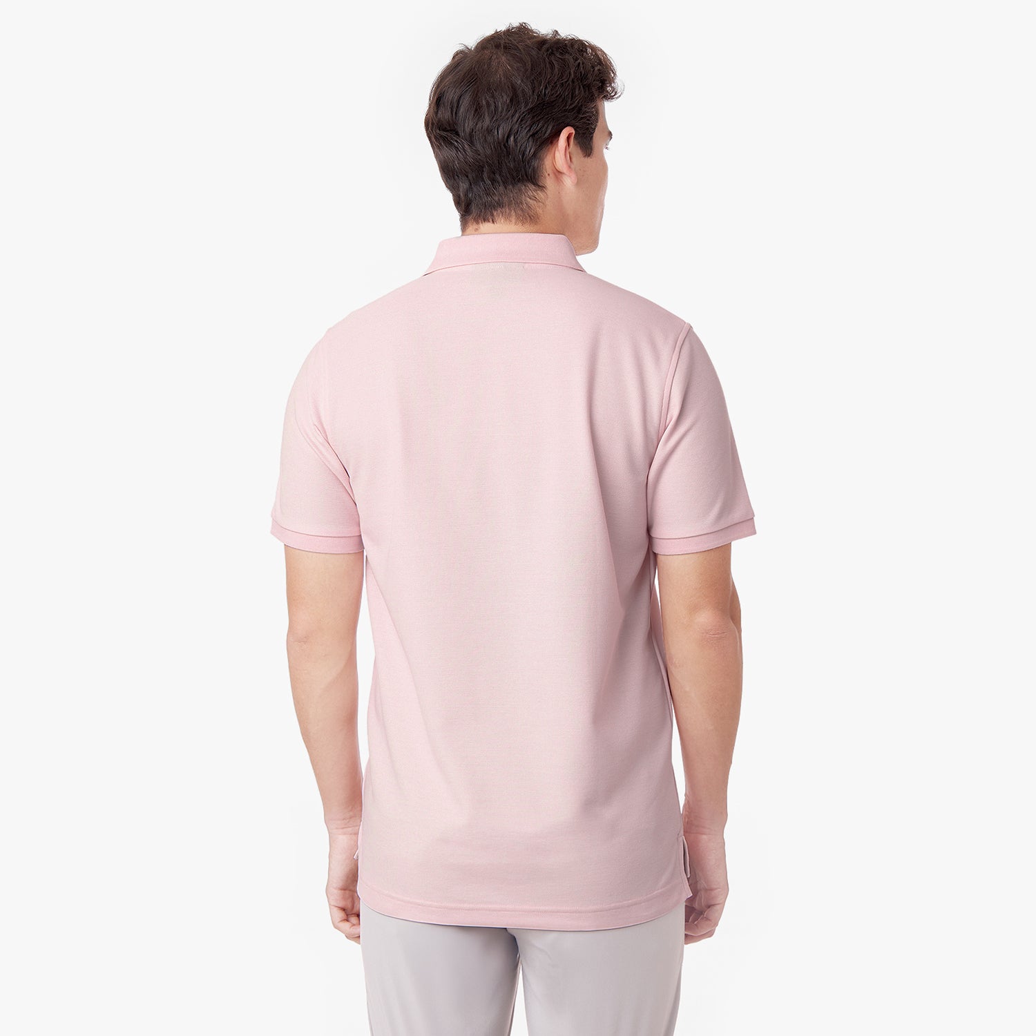 Back view of a male model wearing a pink polo shirt and light grey pants