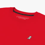 A close-up of the neckline and upper chest area of a red T-shirt, featuring a small embroidered white dog logo on the left side. The black inner collar lining displays the repeated 'JAMES BARK' branding, and the inside label reads 'JAMES BARK MAKE YOUR BARK