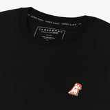 Close-up view of a black t-shirt featuring a small embroidered orange and white dog logo on the left chest. The neck label inside reads 'James Bark, Make Your Bark, Est. 2015, 100% Pima Cotton, Made in Peru' with branded James Bark trim around the collar.