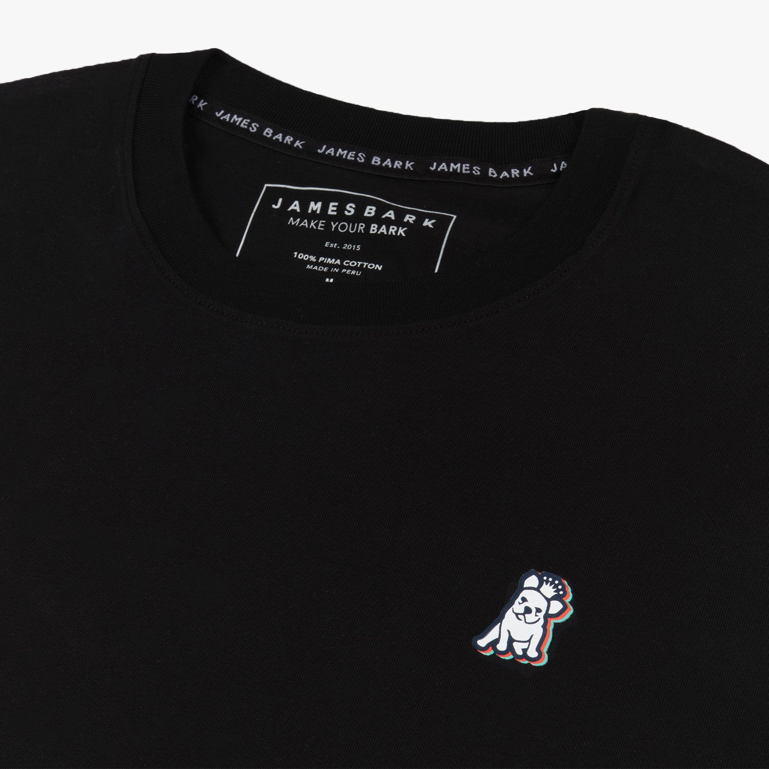 Flat-lay of the front of the black t-shirt: Black t-shirt displayed on a white surface, with the embroidered dog logo visible on the upper left side.