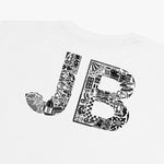 Close-up of the back of a white t-shirt featuring a large 'JB' monogram filled with intricate black and white illustrations. The design incorporates various elements, including architectural landmarks, floral patterns, and other abstract shapes, giving it a unique and artistic flair.