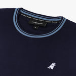 Close-up of the neckline and small dog graphic on the chest of the navy blue T-shirt with light blue trim.