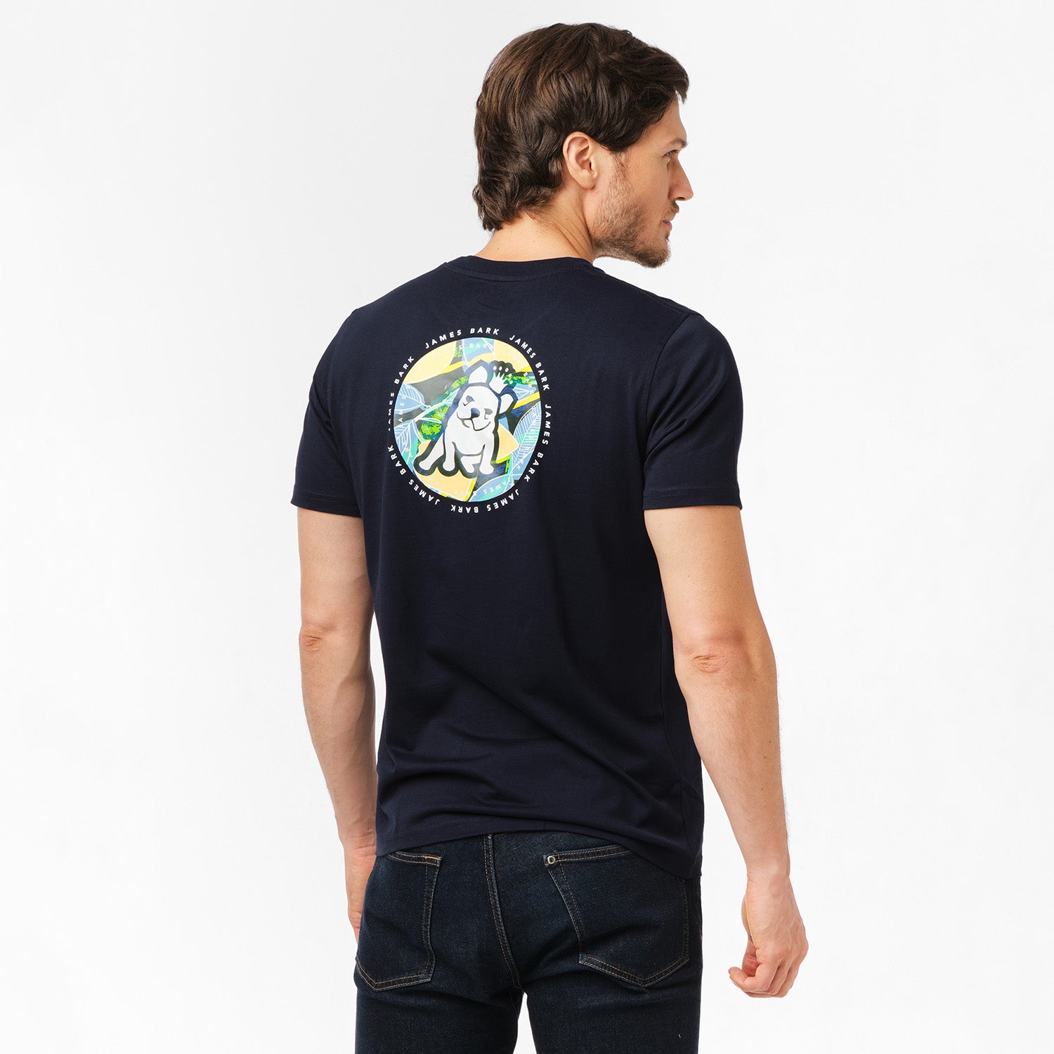 Man wearing a navy blue t-shirt with a large circular graphic on the back featuring a colorful design of a dog with mountains and a sun in the background.