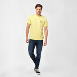 Man wearing a yellow t-shirt with a small graphic on the left chest, walking casually with one hand in his pocket.