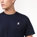 Close-up of the navy blue t-shirt's left chest, showing a small logo design.