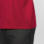 Close-up of the lower hem of the plain red T-shirt, showing the stitching detail over dark pants.