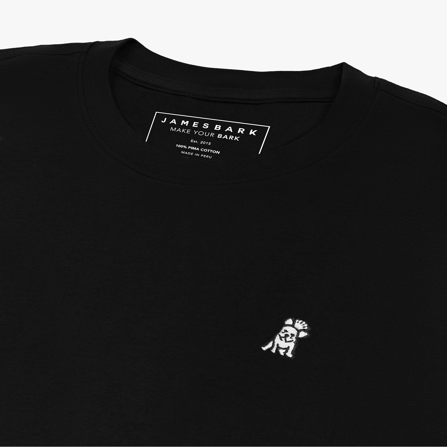 Close-up of the inner label and embroidered logo on the black t-shirt: A detailed shot showing the inner neck label with branding and care information, as well as the small white embroidered dog logo on the left chest.