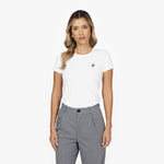 Front waist-up view of a female model wearing a white crew neck t-shirt with a small gold embroidered logo on the left chest, paired with grey trousers