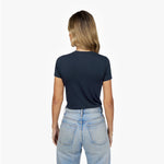 Back waist-up view of a female model wearing a plain navy blue short-sleeve crew neck t-shirt and light wash jeans