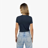Back waist-up view of a female model wearing a plain navy blue short-sleeve crew neck t-shirt and light wash jeans