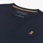 Angled close-up of the neckline of a navy blue crew neck James Bark t-shirt, highlighting the brand label, contrast neck tape, and gold embroidered dog logo