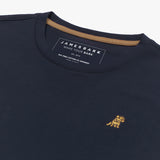Angled close-up of the neckline of a navy blue crew neck James Bark t-shirt, highlighting the brand label, contrast neck tape, and gold embroidered dog logo