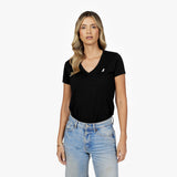 Front waist-up view of a female model wearing a black v-neck t-shirt with a small white embroidered logo on the left chest, paired with light wash jeans