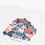 Back flat-lay view of the white t-shirt showing the colorful graphic of buildings and a dog illustration.