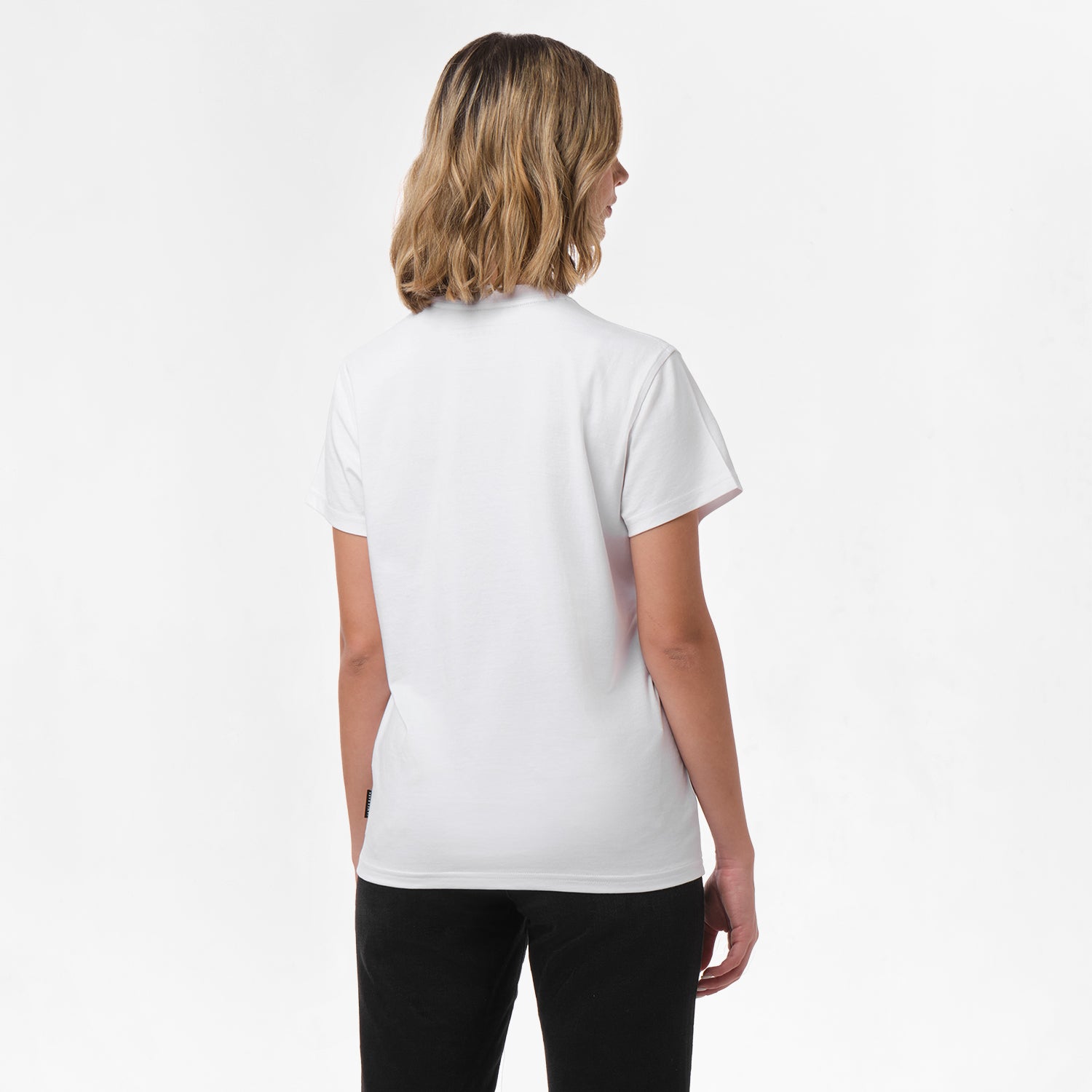 A woman is shown from behind, wearing the white T-shirt paired with black pants. No design is visible on the back.