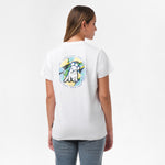 A woman is shown from behind, wearing a white T-shirt with a large circular graphic on the back. The design features a dog sitting in front of a tropical background with the text "James Bark Privé Society" around the circle. She pairs the shirt with light blue jeans.