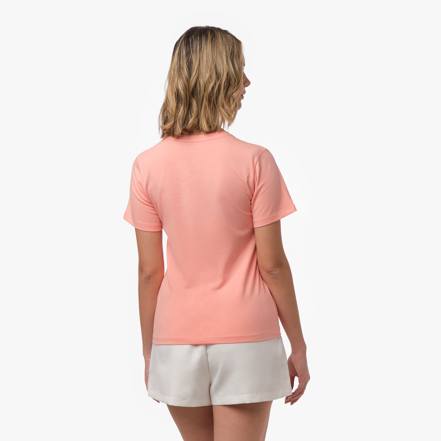 Back view of a woman wearing a plain peach-colored t-shirt and white shorts