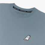 Close-up of the woman's chest area showing the small embroidered logo on the front of the blue-gray t-shirt.