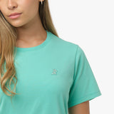 Close-up of the small, white embroidered dog logo on the left chest of the mint green t-shirt