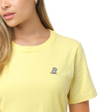 Close-up of the small, white embroidered dog logo on the left chest of the pale yellow t-shirt
