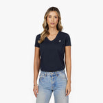 Front waist-up view of a female model wearing a navy blue v-neck t-shirt with a small white embroidered logo on the left chest, paired with light wash jeans