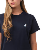 A close-up of the woman wearing the navy blue T-shirt, focusing on the chest area with the small embroidered dog logo.