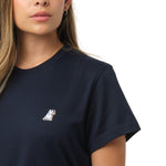 A close-up of the woman wearing the navy blue T-shirt, focusing on the chest area with the small embroidered dog logo.