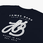 A close-up of the back design on the navy blue T-shirt, showing the large white graphic with "James Bark Privé Society" and the rope initials "JB."