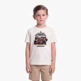 A young boy modeling a cream-colored T-shirt with a James Barker racing graphic