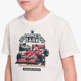 A child wearing a cream-colored T-shirt with a graphic print of a red James Bark F1 car and checkered flags.