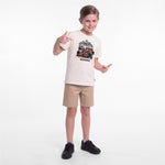 A young boy modeling a cream-colored graphic T-shirt, khaki shorts, and black sneakers