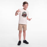 A young boy modeling a cream-colored graphic T-shirt, khaki shorts, and black sneakers
