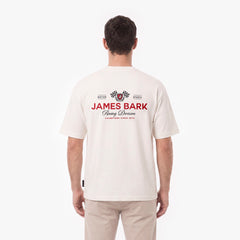 A man viewed from behind wearing a cream-colored T-shirt with a red and black James Bark Racing Division graphic on the back