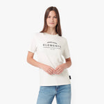 A woman modeling a cream-colored short-sleeve t-shirt with 'JAMES BANK ELEMENTS' printed in black on the chest
