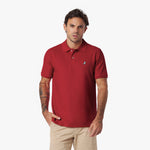 Man wearing a red polo shirt with a small logo on a white background