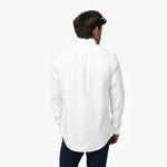 Back view of a man wearing a white long-sleeved shirt and navy blue pants against a white background, showing a box pleat on the back