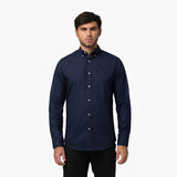 Front view of a man wearing a navy blue long-sleeved button-down shirt and black pants against a white background